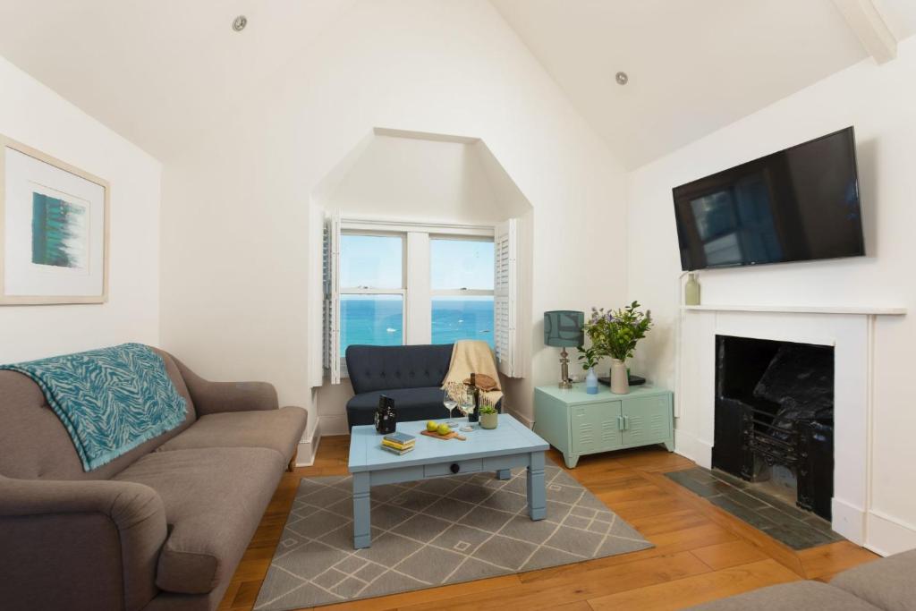 een woonkamer met een bank en een open haard bij Mordros, St Ives in St Ives