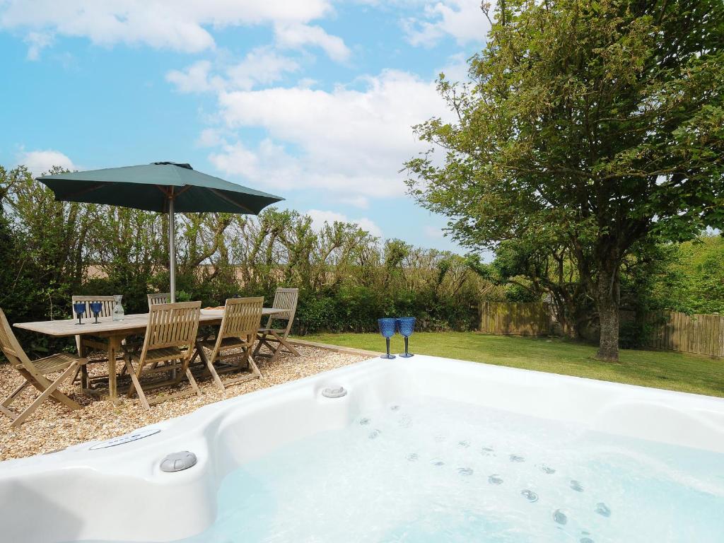 a bath tub with a table and an umbrella at Carvannel Cottages in Camborne