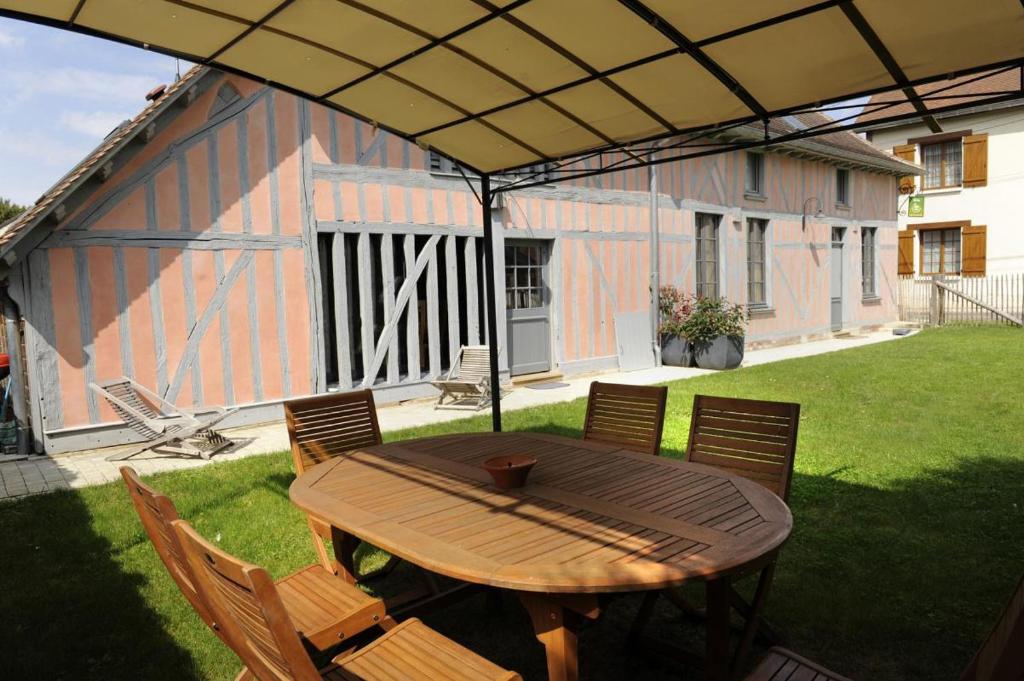 einen Holztisch und Stühle unter einem Sonnenschirm in der Unterkunft Le pic drille in Charmont-sous-Barbuise