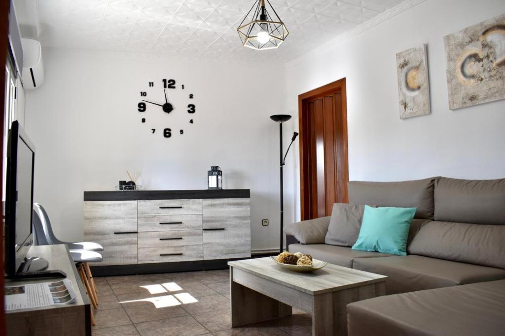 Una sala de estar con un sofá y un reloj en la pared. en Alma del Tajo VUT, en Villamanrique de Tajo