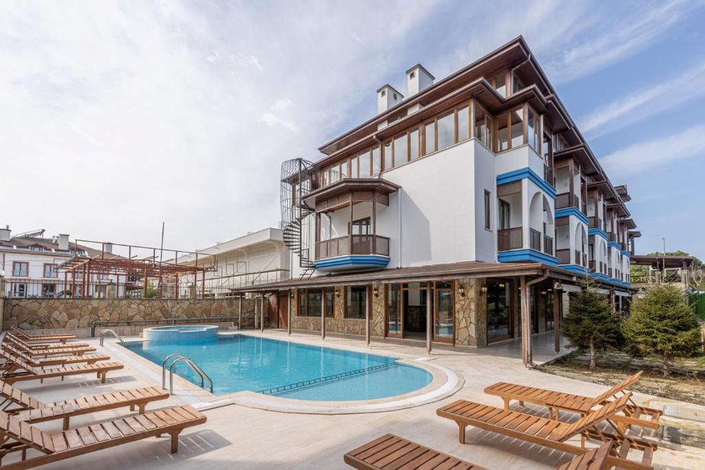 an apartment building with a swimming pool and chairs at Olinda Hotel & Spa in Sile