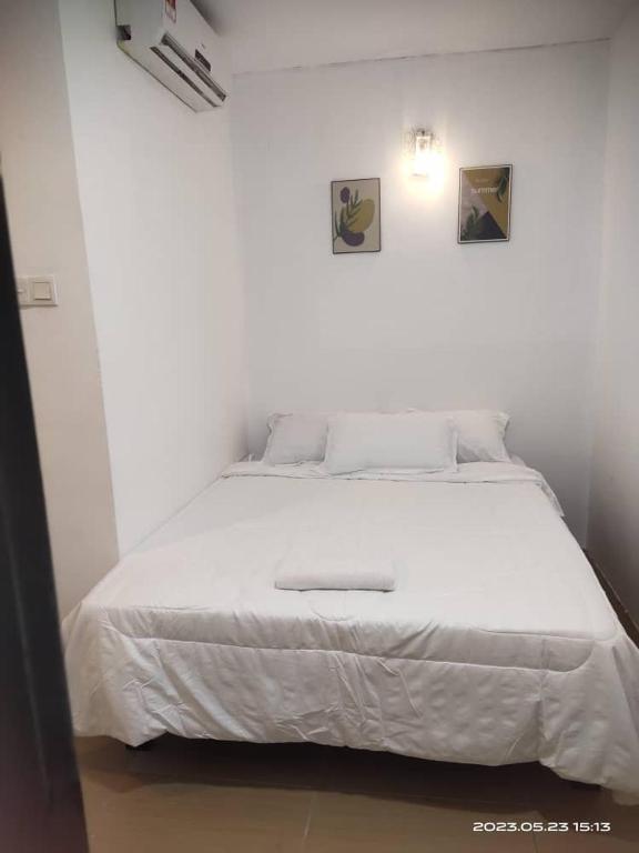 a white bedroom with a white bed in a room at Bulat Cottage in Pantai Cenang