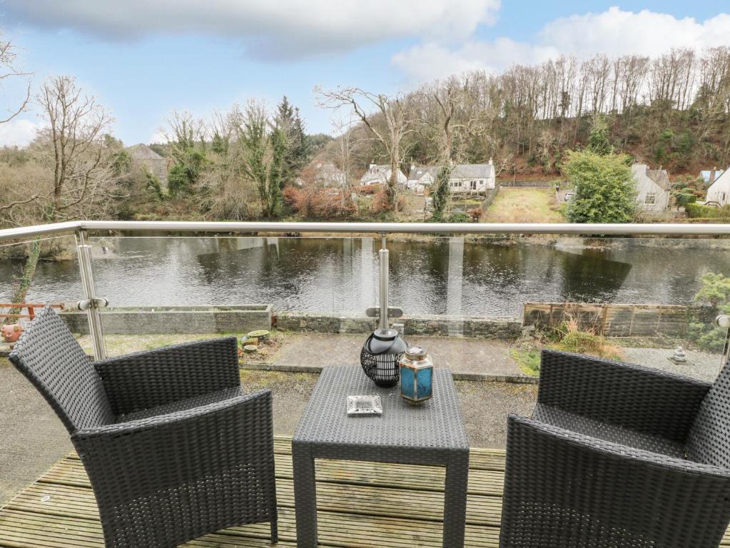 ein Tisch und Stühle auf einer Terrasse mit Blick auf einen See in der Unterkunft Barley Cottage in Newton Stewart