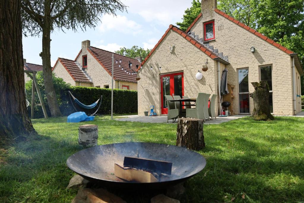 a fire pit in the yard of a house at 7 person House with swing, firepit, hammock, garden, swimming lake, child friendly, in- and outside playground, and great coffee in Ewijk