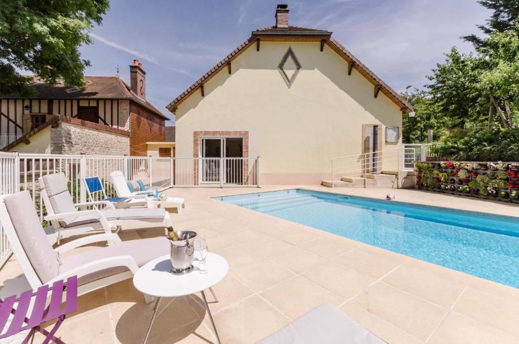 a swimming pool with white chairs and a house at Le gite du petit ecureuil in Balnot-sur-Laignes