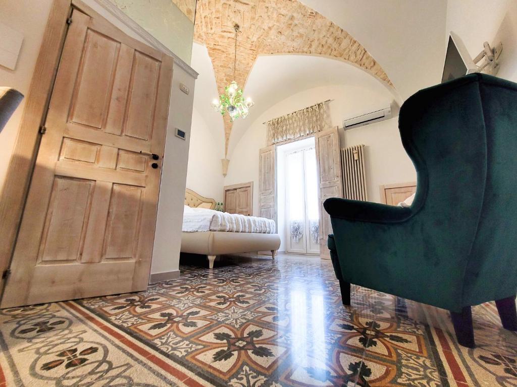 a living room with a green chair and a bedroom at ROSSINI GUEST HOUSE in Martina Franca