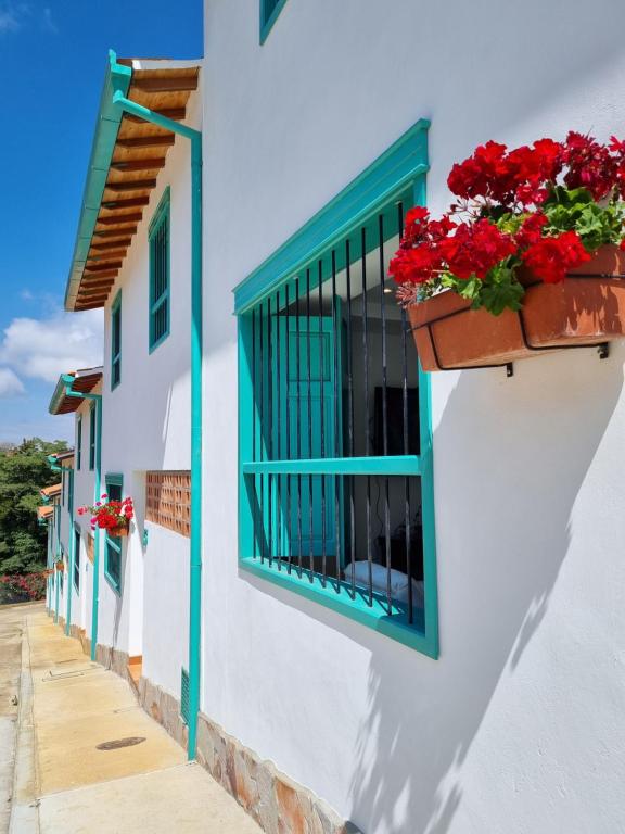 un edificio blanco con ventanas azules y flores rojas en Casa Celeste, en Zapatoca