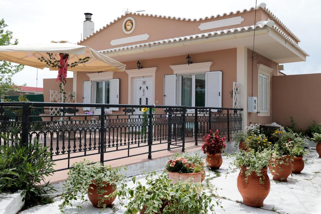 Chrysanthi's House في Áyios Kírikos: منزل به نباتات الفخار أمام السياج