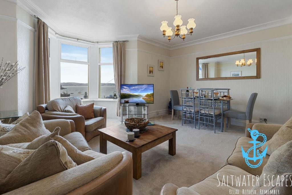a living room with couches and a table at Sea Spray Villa, Brixham in Brixham