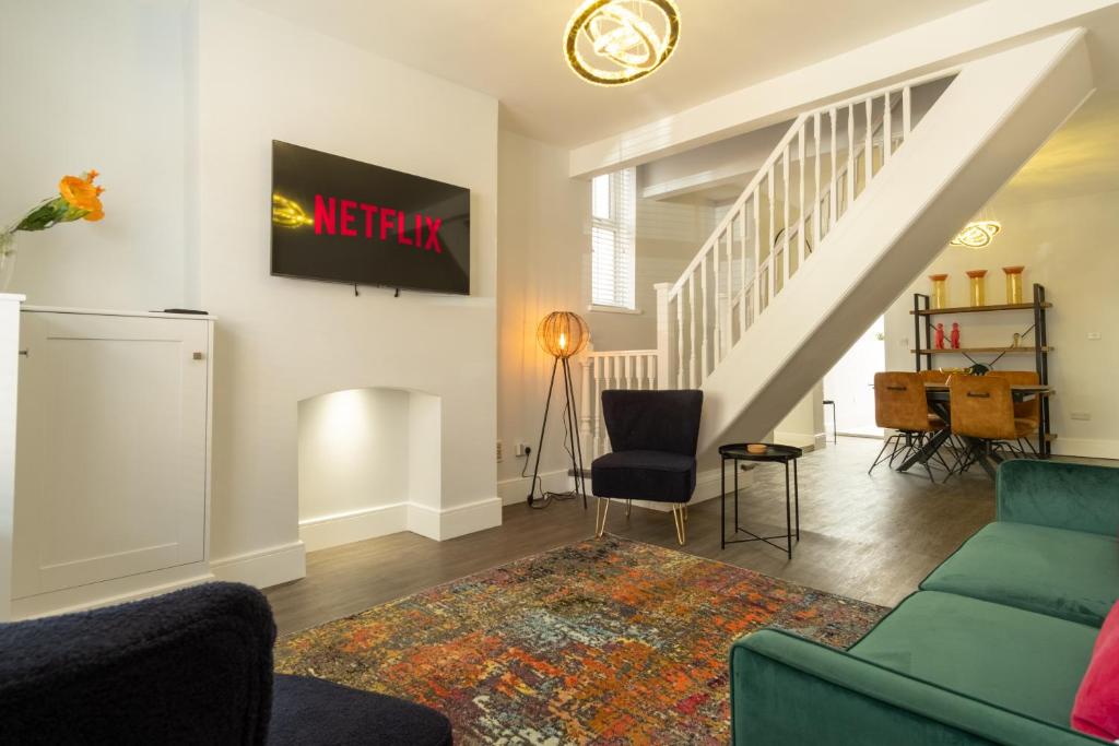 a living room with a couch and a tv on the wall at Sparkenhoe House in Hugglescote