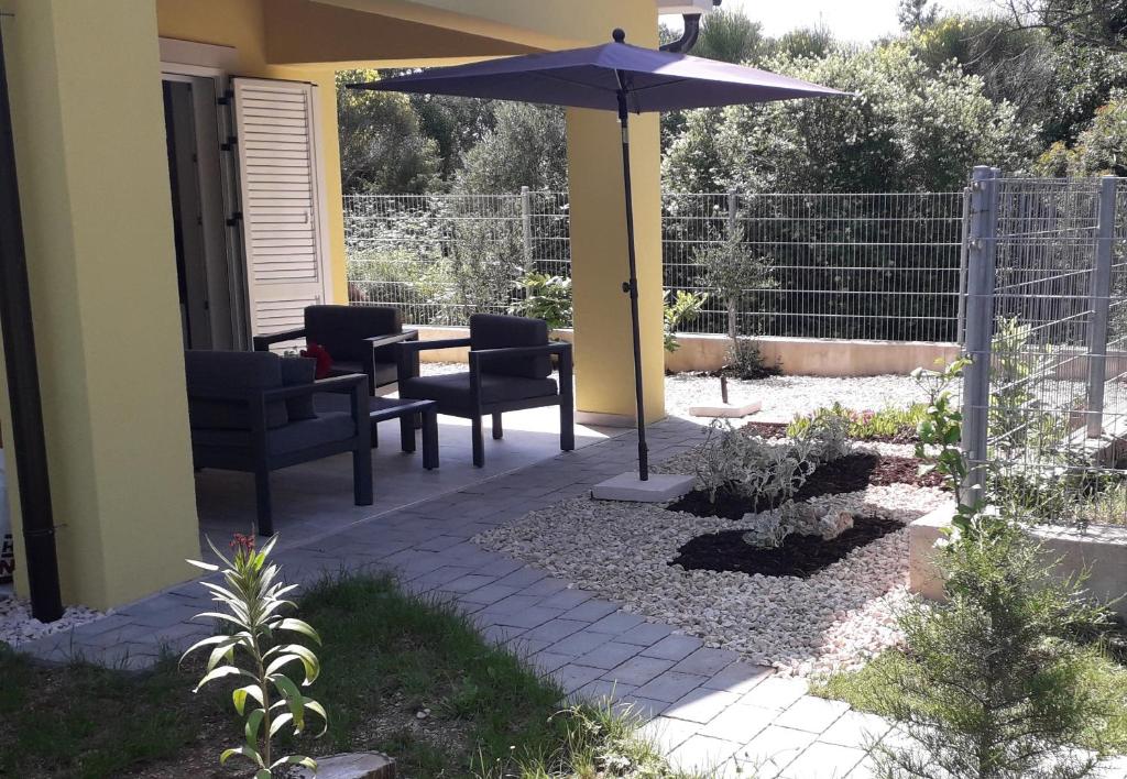 un patio con mesa, sillas y sombrilla en Vivi holiday house for 4 people, en Nerezine