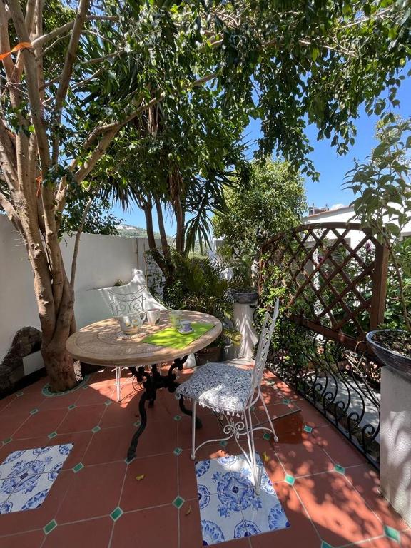 a table and chairs on a patio with a tree at Arabesque in Lacco Ameno