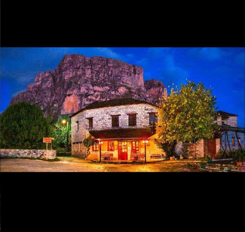 a stone building with a mountain in the background at Karpouzis guesthouse in Víkos