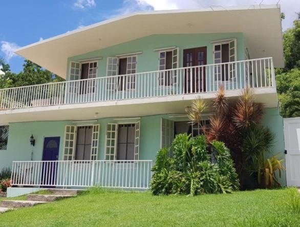 Casa verde y blanca con balcón blanco en Casa Mia Guest House, en Rincón