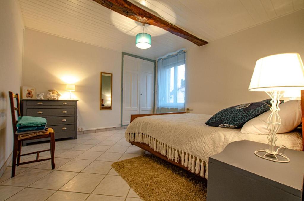 um quarto com uma cama e uma mesa com um candeeiro em Le gite de saint martin em Mailly-le-Camp