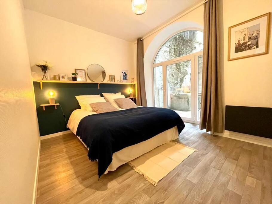 una camera con un grande letto e una grande finestra di Le Patio - Rénové et Proche lac a Nantua