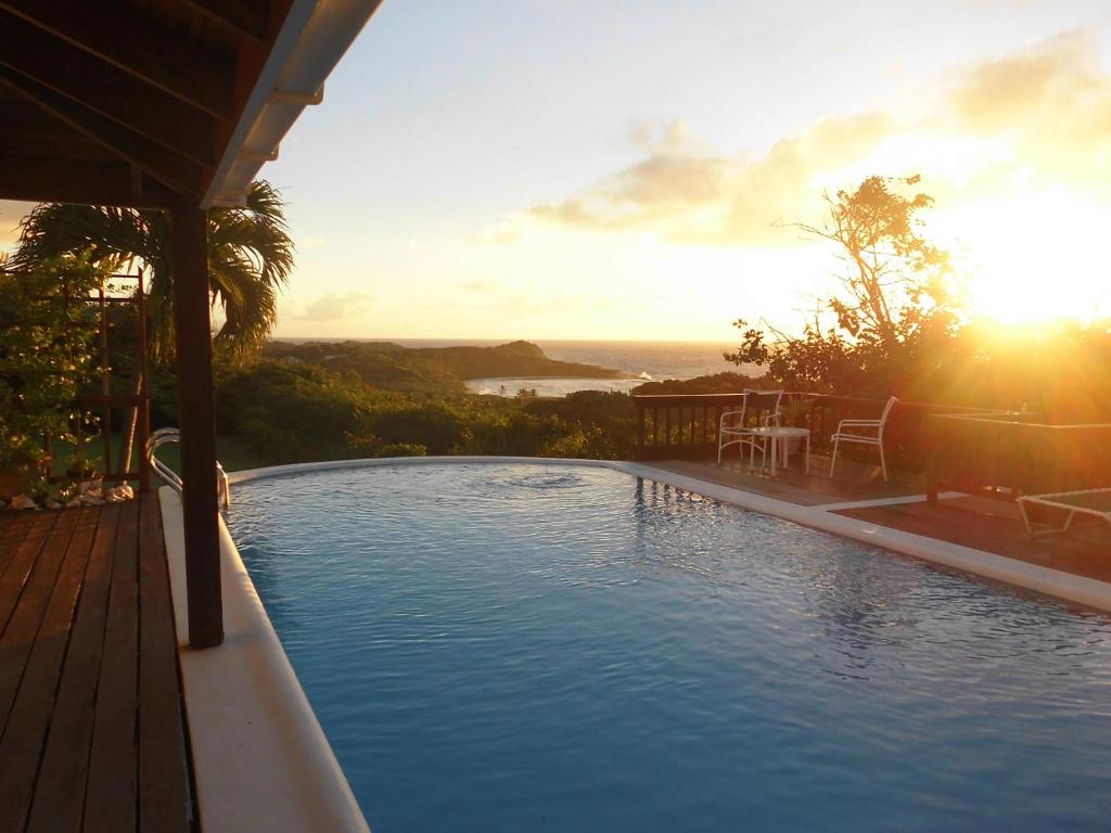 una piscina con puesta de sol en el fondo en Villa Romana, en Freetown Village