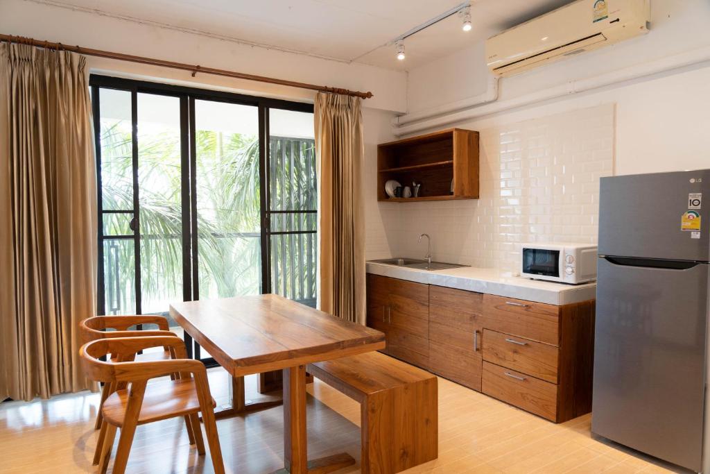 a kitchen with a wooden table and a refrigerator at Chiang Mai Mansion 2 in Chiang Mai