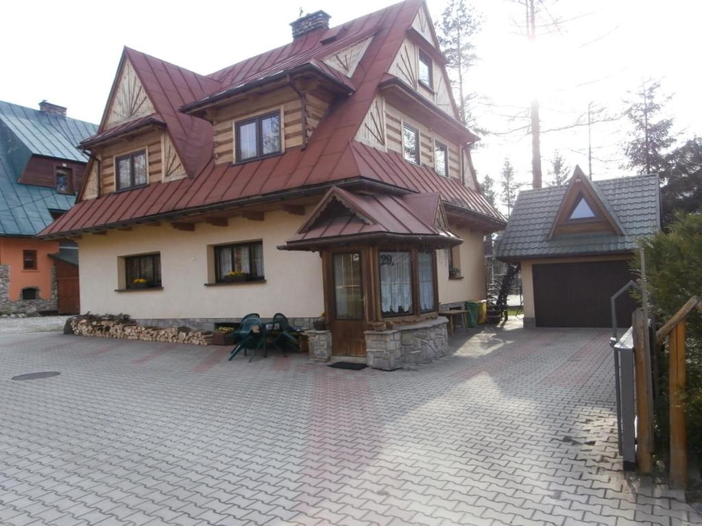 une maison avec un toit rouge dans une allée en briques dans l'établissement Pokoje Gościnne Grażyna Kozioł, à Zakopane
