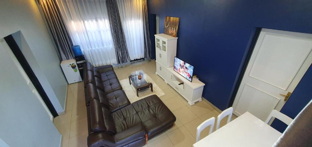 a living room with a leather couch and a tv at Cozy Nest Oasis - Serviced Apartment in Kigali