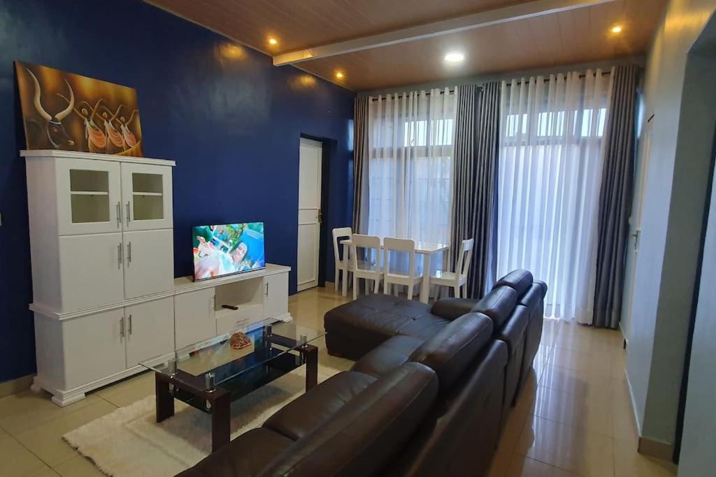 a living room with a couch and a dining room at Cozy Nest Oasis - Serviced Apartment in Kigali