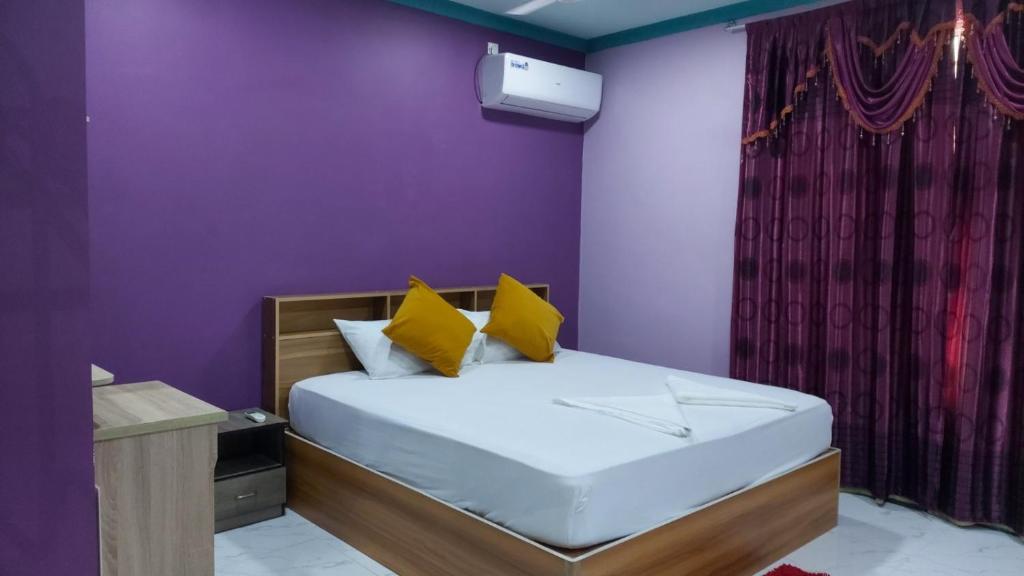 1 dormitorio con 1 cama con paredes moradas y almohadas amarillas en Sunny Side inn en Midu