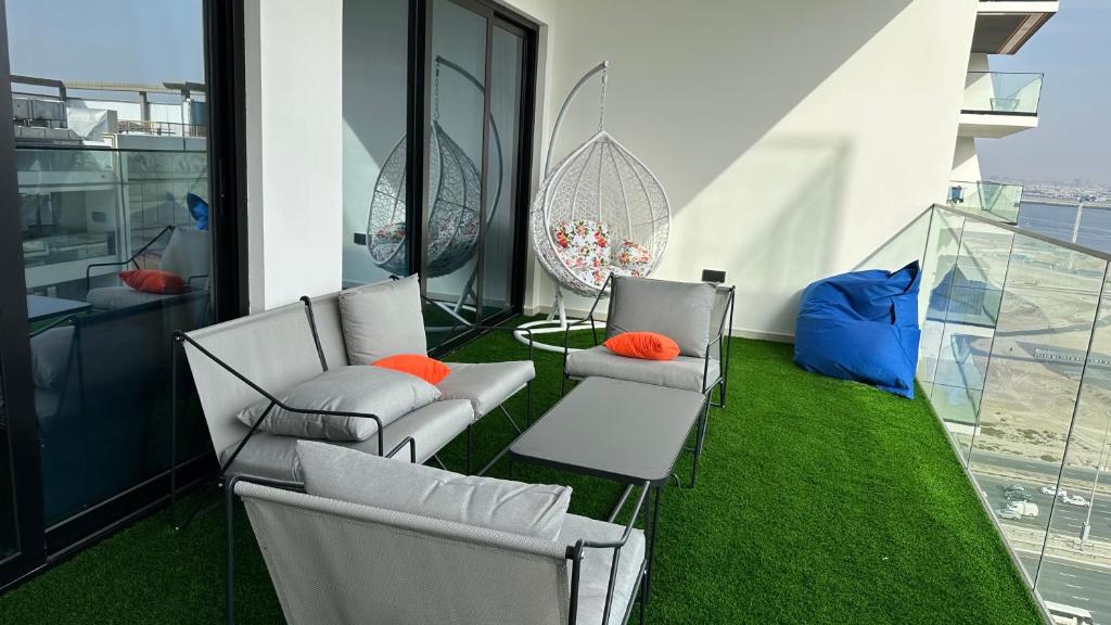 a balcony with white chairs and green grass at VIP 2 bedrooms 5 minutes from Burj Khalifa in Dubai