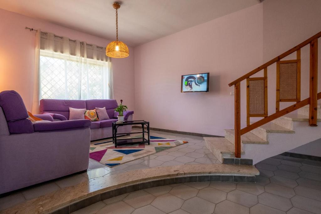 salon z fioletową kanapą i schodami w obiekcie Butterfly House w mieście Trappeto