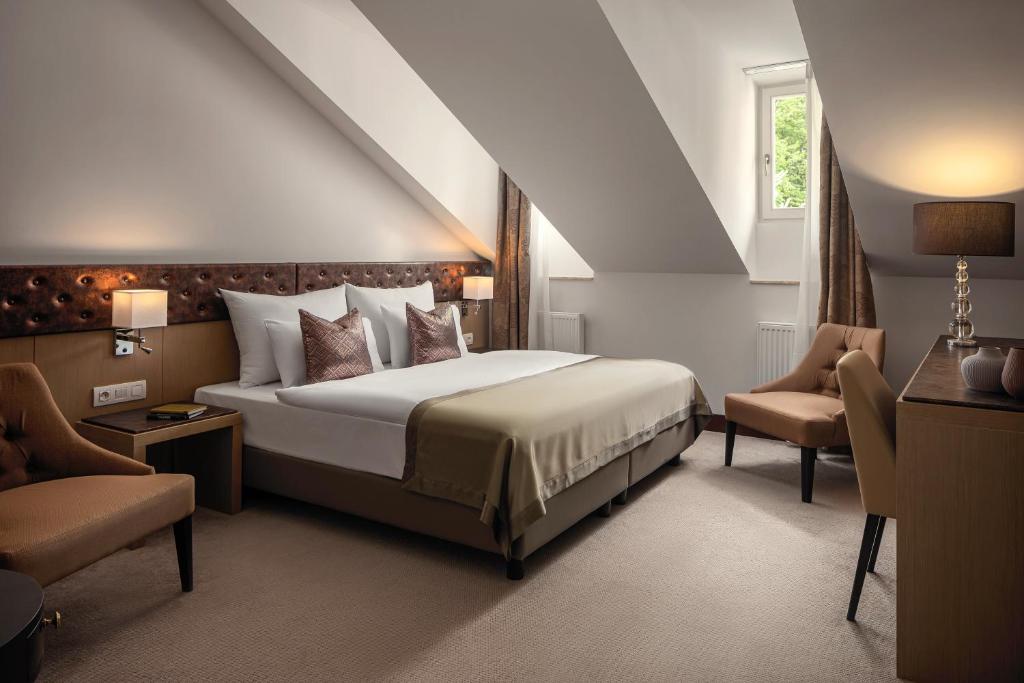 a bedroom with a large bed and two chairs at Boutique Hotel Saxonia in Karlovy Vary