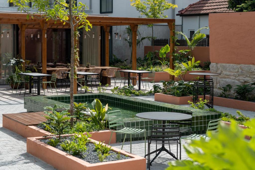 The Editory Garden Porto Hotel في بورتو: ساحة مع طاولات وكراسي وأشجار