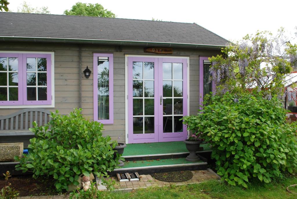 una pequeña casa con una puerta púrpura y algunos arbustos en B&B Öland, en Ottoland