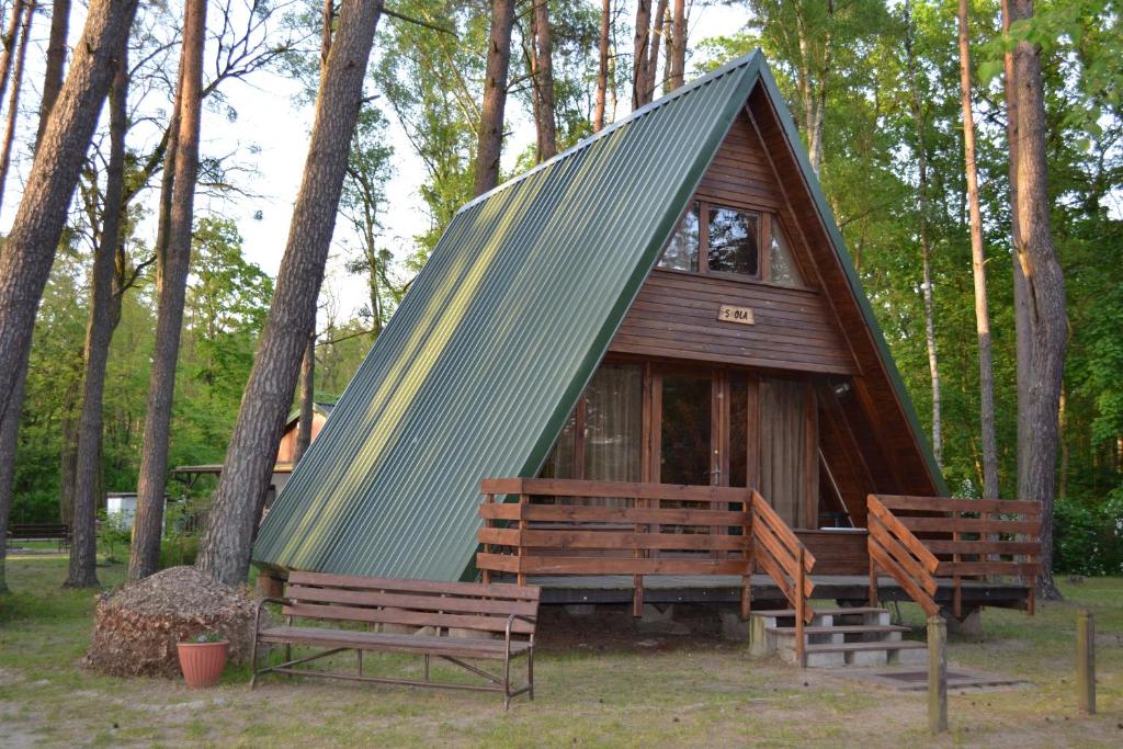 eine kleine Hütte mit zwei Bänken in einem Wald in der Unterkunft Nowa Holandia in Sieraków