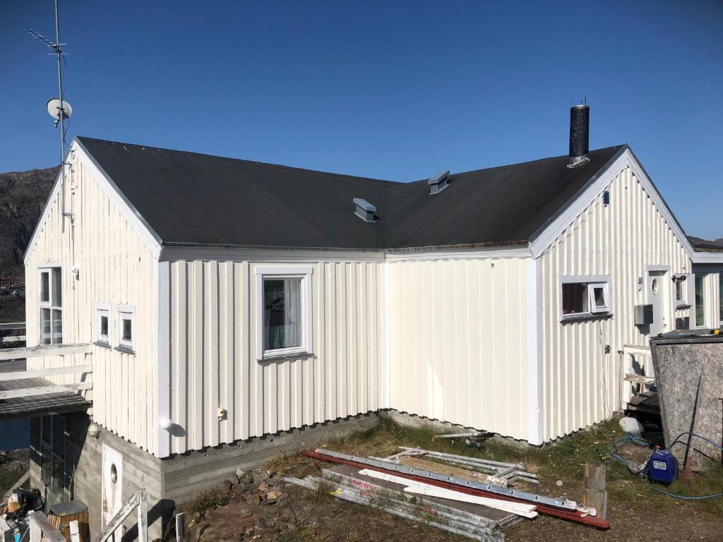 ein Haus im Bau mit schwarzem Dach in der Unterkunft Dejlig og et godt hus, Hotel in Sisimiut