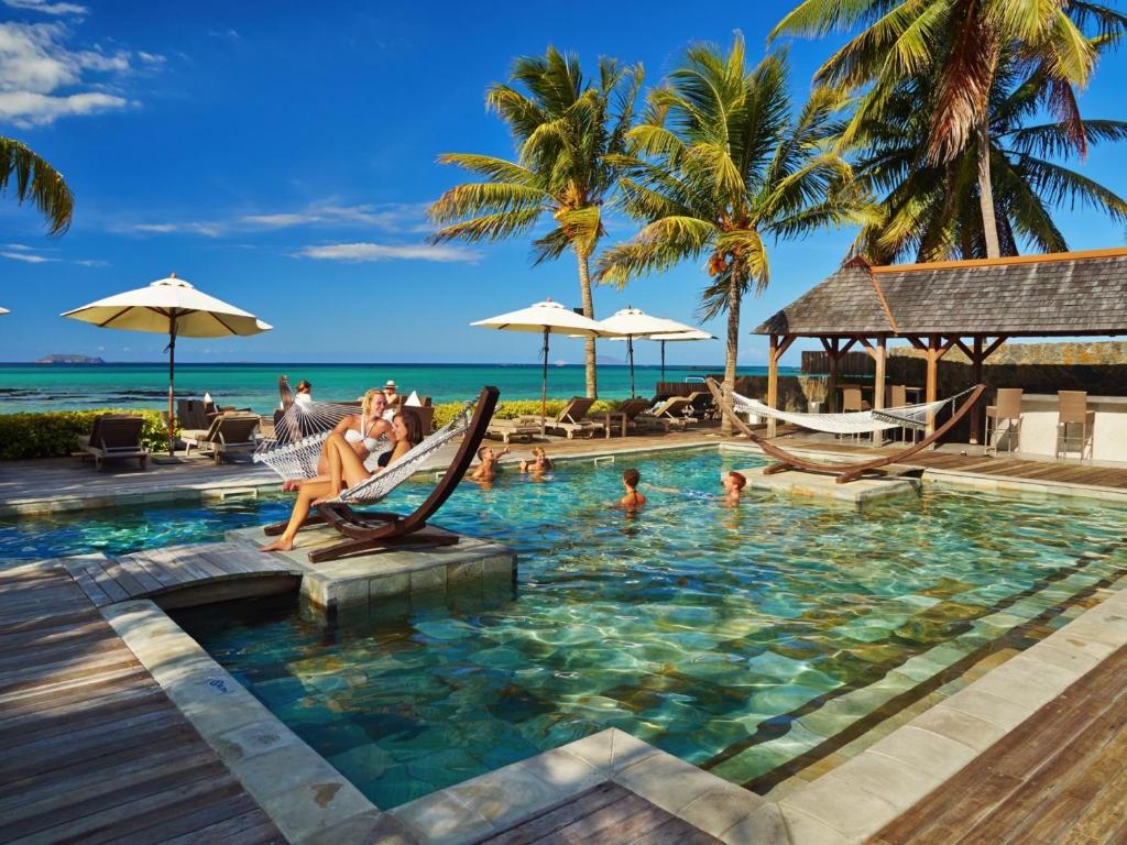 un grupo de personas sentadas en una piscina en un complejo en Cape Point Seafront Suites & Penthouse by LOV, en Cap Malheureux