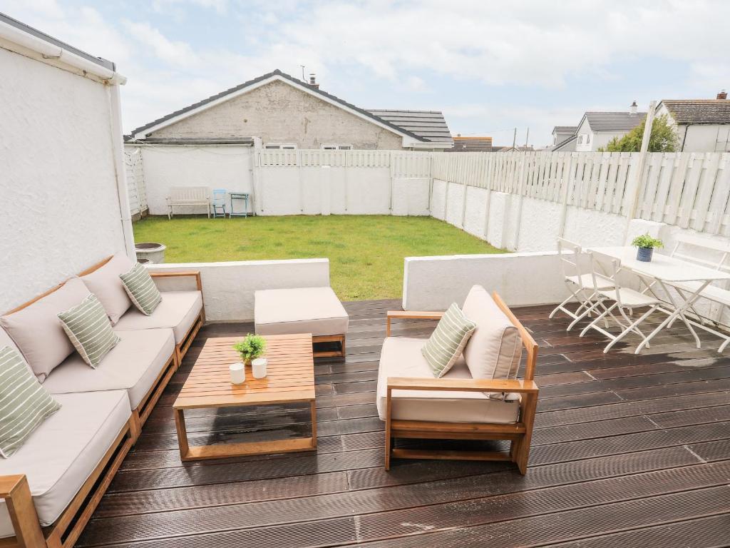 a patio with a couch and chairs and a table at 31 Sisial Y Mor in Rhosneigr