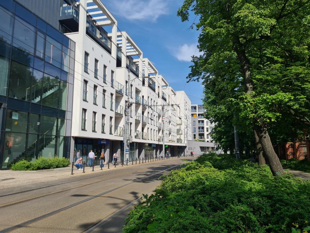 een straat in een stad met gebouwen en een boom bij Mostowa 23 BRUNO Apartment, self check-in 24h, free parking, air-conditioning in Poznań