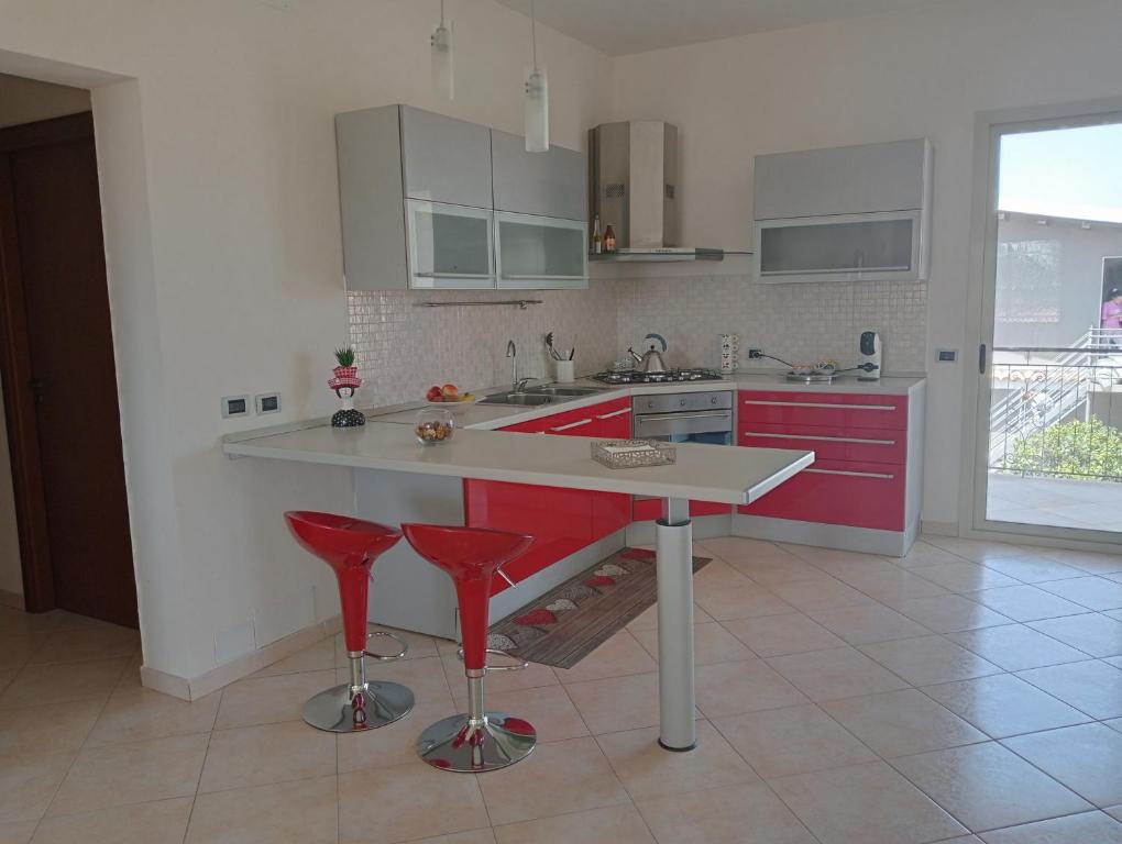 a kitchen with red cabinets and red bar stools at Villa Gelsemium in Siracusa