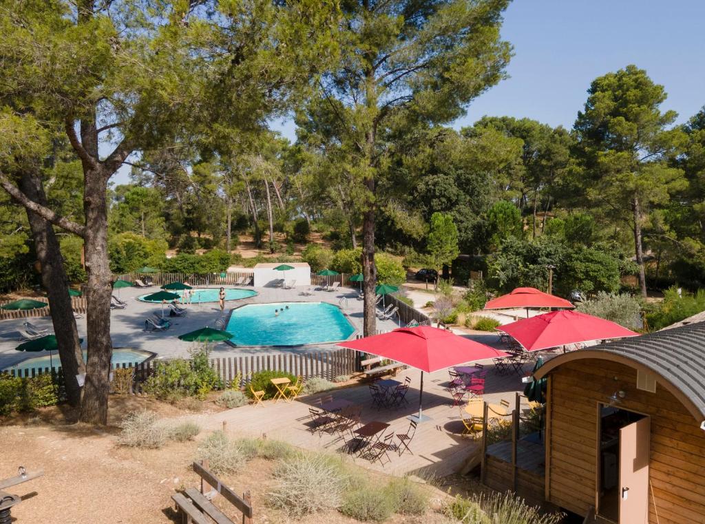 an overhead view of a pool with red umbrellas at Huttopia Fontvieille in Fontvieille