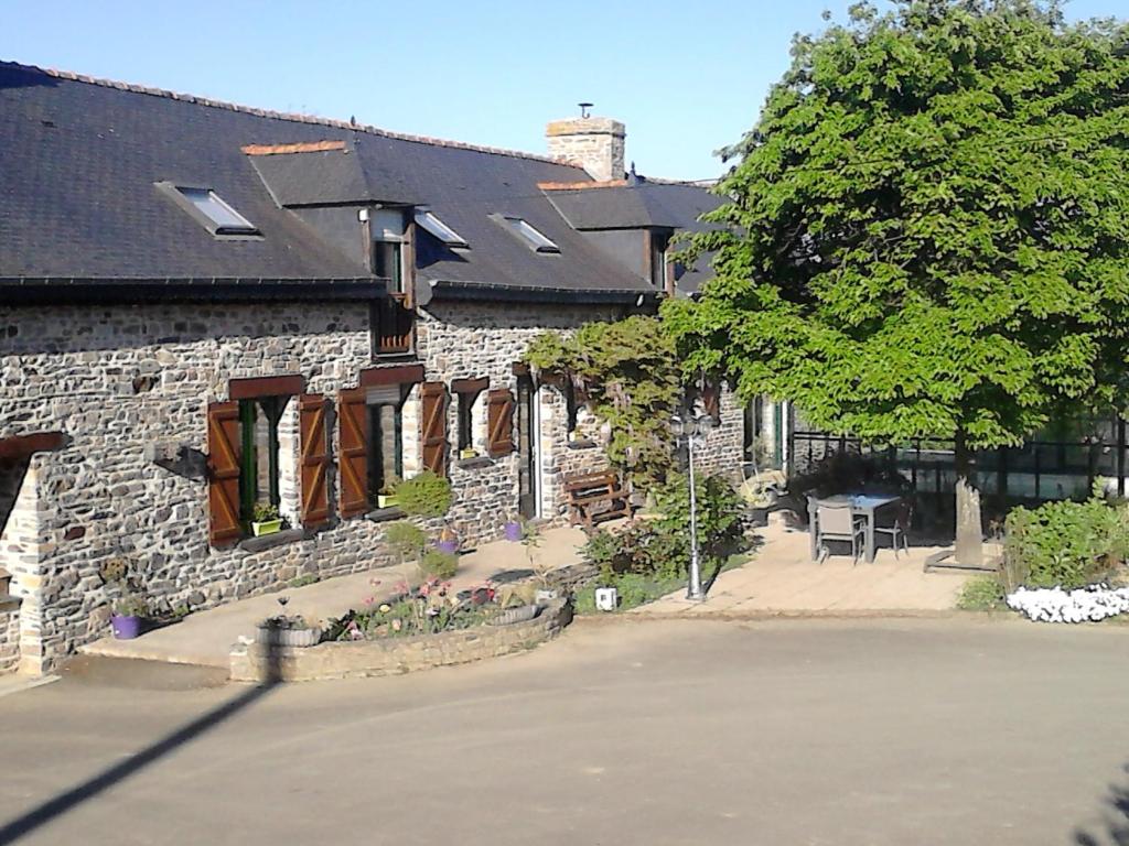 ein Steinhaus mit einem Tisch und einem Baum in der Unterkunft La P'tit' Fugue in La Bouexière