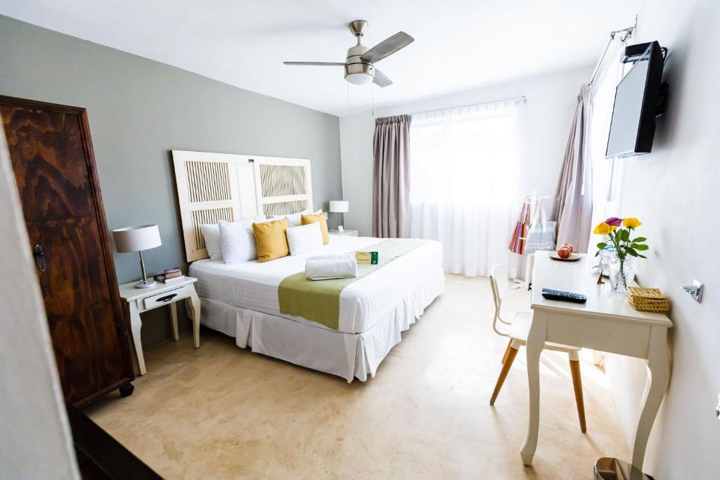 Hotel Siesta Holbox في جزيرة هول بوكس: غرفة نوم بسرير ومكتب وتلفزيون