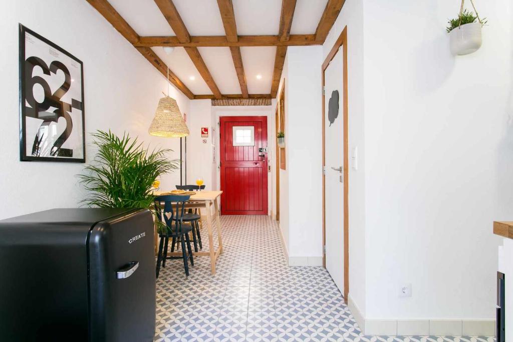 un couloir avec une porte rouge et une table avec des chaises dans l'établissement Estudio NovoCentro CongressosLX Factory, à Lisbonne