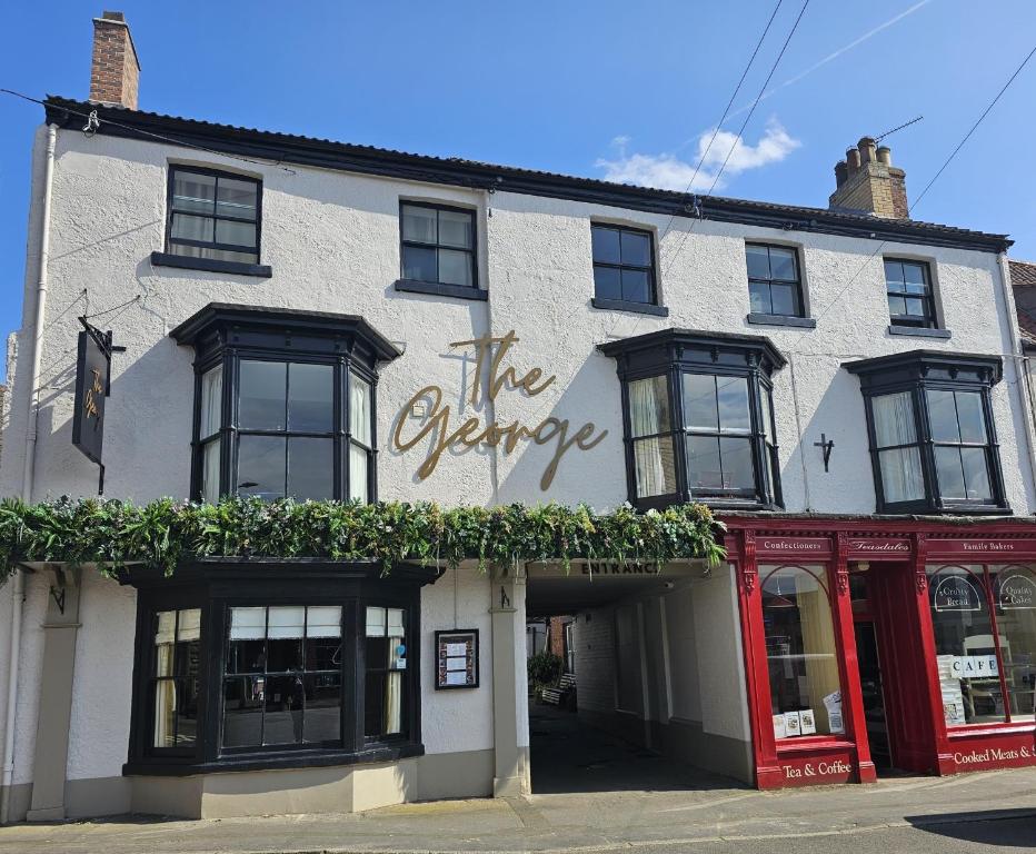 Ein weißes Gebäude mit dem höchsten Schild drauf. in der Unterkunft The George Hotel in Kirton in Lindsey