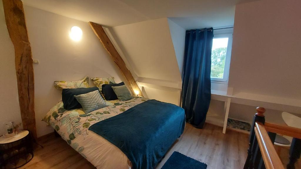 a bedroom with a bed with blue sheets and a window at Gite NATURALLY CALM in Montbray