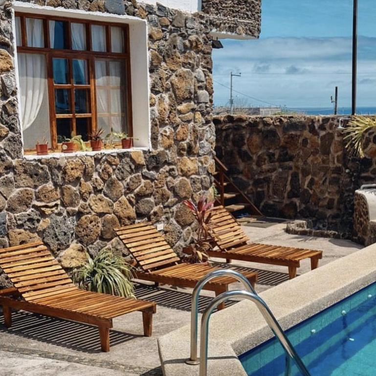 a patio with two benches and a swimming pool at Hotel Pimampiro in Puerto Baquerizo Moreno