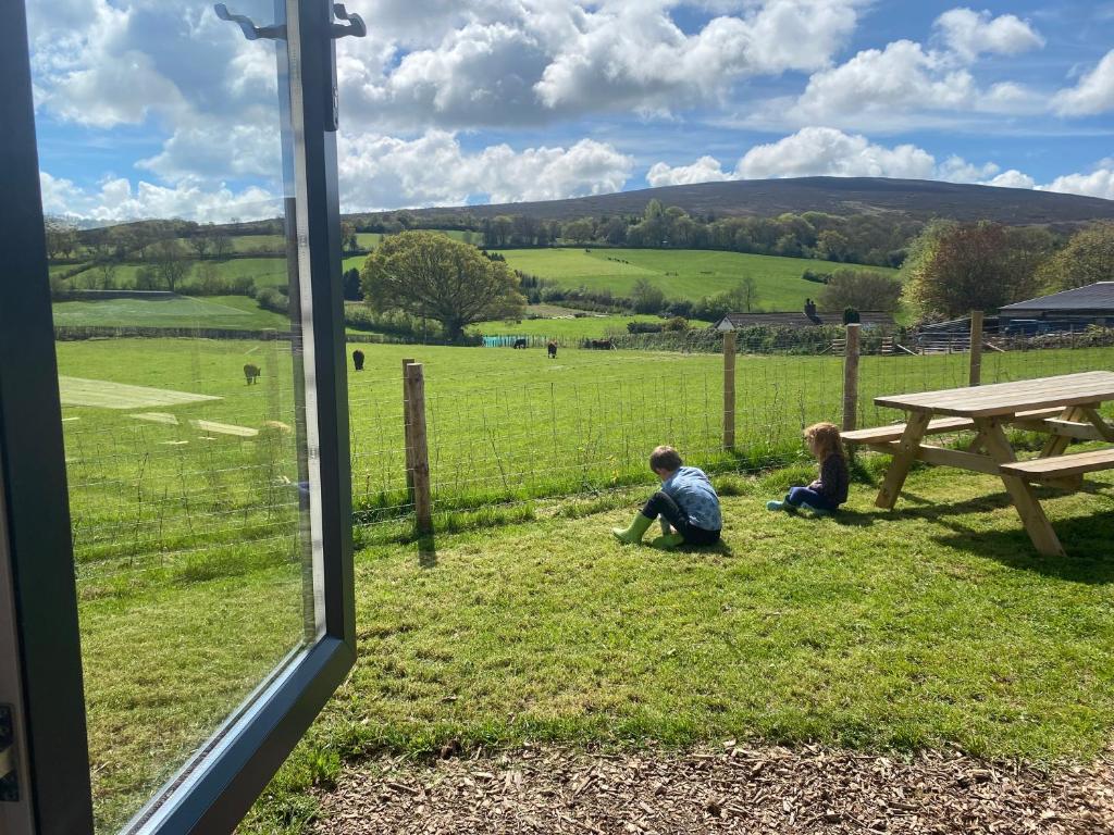 two children sitting in the grass next to a picnic table at Impeccable shepherds hut sleeping up to 4 guests in Minehead