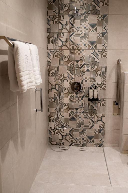 a bathroom with a shower with a tile wall at Nissos Apartments in Myrina