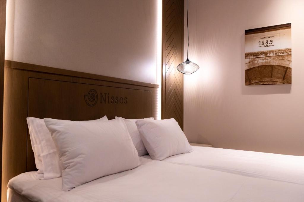 a bedroom with a bed with white sheets and pillows at Nissos Apartments in Myrina