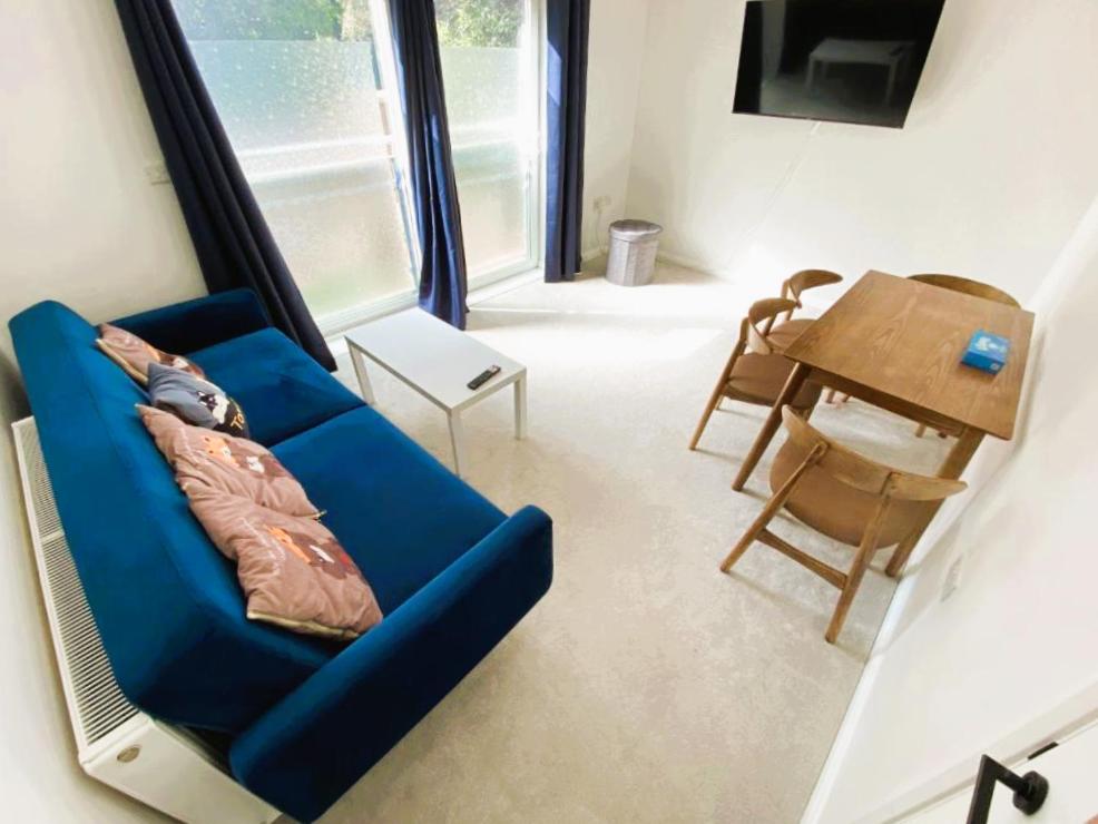 a living room with a blue couch and a table at Modern Peaceful Flat in Town in Bournemouth