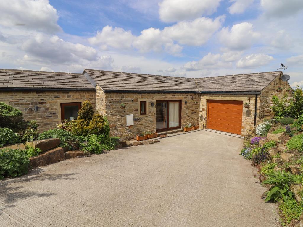a stone house with a garage with a red door at Moorbottom Stables in Halifax