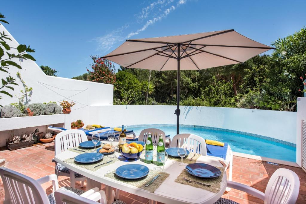 un tavolo con ombrellone su un patio con piscina di Victory Village Beach Villa - Quinta do Lago a Quinta do Lago